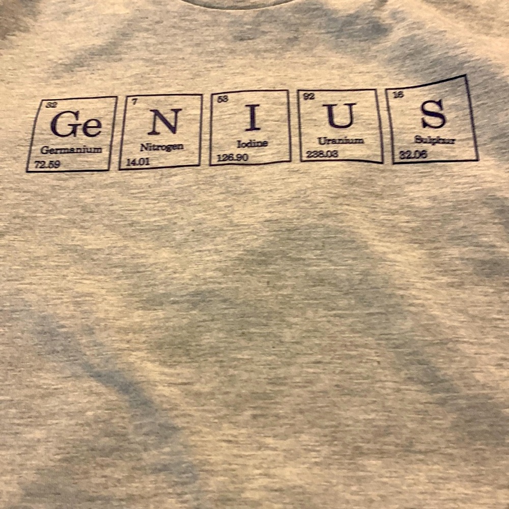 Light grey tshirt. It has genius written at the top of the tshirt.